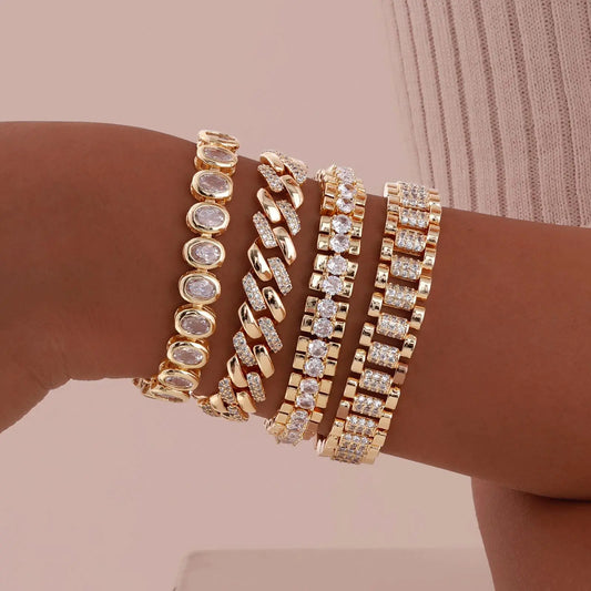 Gold bracelets with diamond accents on a wrist against a beige background
